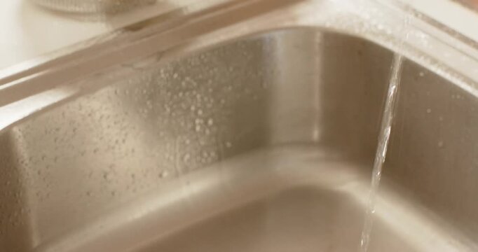 Female hands starting faucet and washing potato under water in kitchen sink cleaning to cook