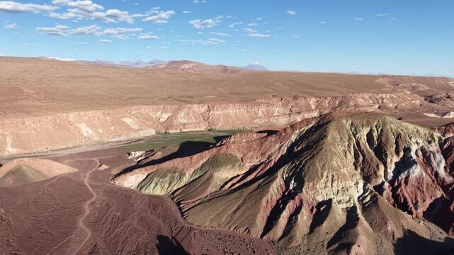 Cinematic aerial flying forward toward the vibrant green, red, and white mineral-rich mountains of Valle del Arcoiris near San Pedro de Atacama at sunset