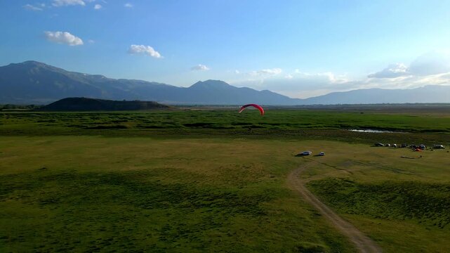 Paraglider soars above lush green fields