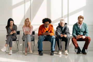 Fototapeta premium Diverse people using smartphones while waiting together