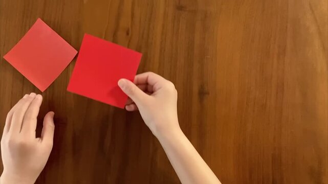 child hands placing second small origami paper