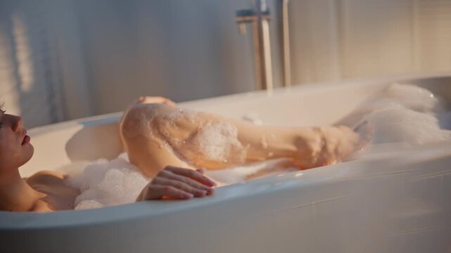 Nude model soaking foamy bubble bath enjoying self care morning routine closeup