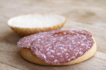 Obraz premium Salami sandwich on sesame seed bun over wooden cutting board