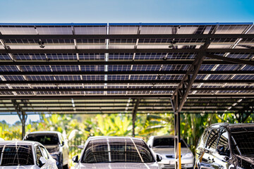 Engineer in safety vest and helmet pointing towards a solar powered carport, illustrating eco-friendly innovation in parking infrastructure. Solar panels provide shade and sustainable energy. © ultramansk