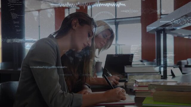 Vertical video: Two women taking notes at study table as waveforms and HUD appearing over laptop