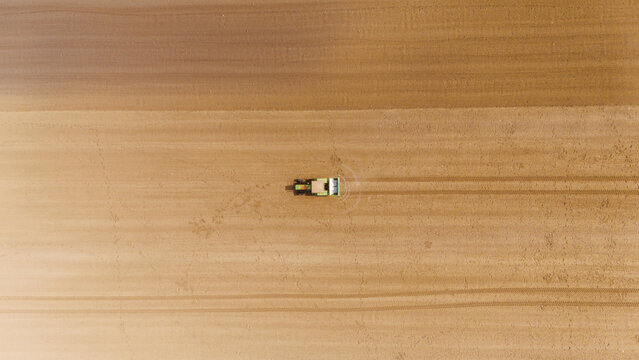 Aerial view of a lone tractor carving lines into the earth, contrasting the freshly tilled soil with the untouched fields, Sremska Mitrovica, Vojvodina, Serbia.