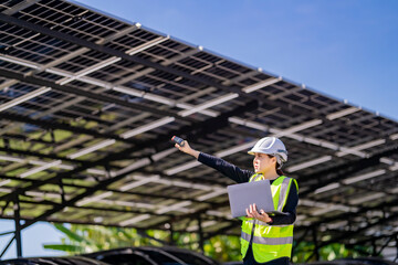 Fototapeta premium Engineer in safety vest and helmet pointing towards a solar powered carport, illustrating eco-friendly innovation in parking infrastructure. Solar panels provide shade and sustainable energy.