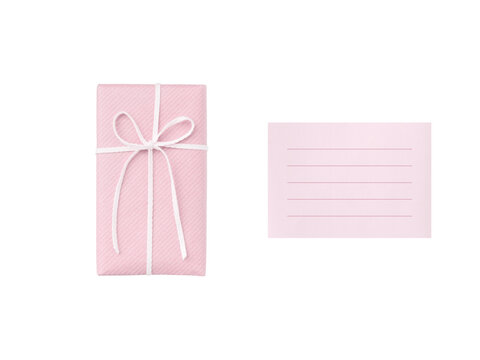Overhead view of a pale pink gift box tied with a white ribbon and a ruled pink card