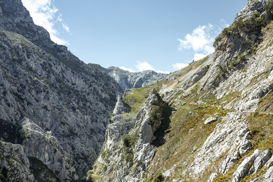 View of a dramatic gorge carved through jagged mountains, where rugged cliffs meet the sky in Picos de Europa, Asturias, Spain.