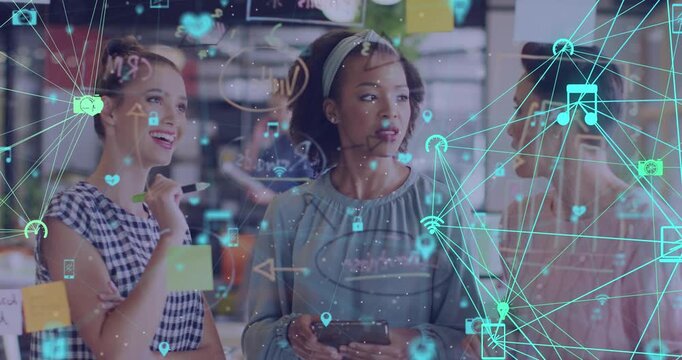 Animation of connected icons forming globe, female coworkers discussing ideas on sticky notes