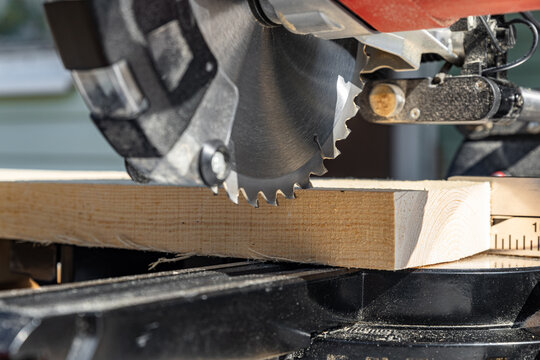 Miter saw tool blade up close for cutting lumber and carpentry. Using a circular saw to cut a wooden board. Blade of a miter saw to cut off the edge of a wooden board, close up.