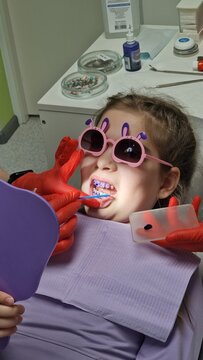 Little girl at dentist wearing playful sunglasses during dental treatment. Child-friendly dental visit illustrating pediatric care, anxiety reduction, and early oral health treatment