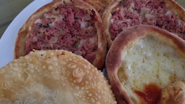 Camera Pulling Back from Calabrese and Cheese Esfirra with Brazilian Pastel on Plate