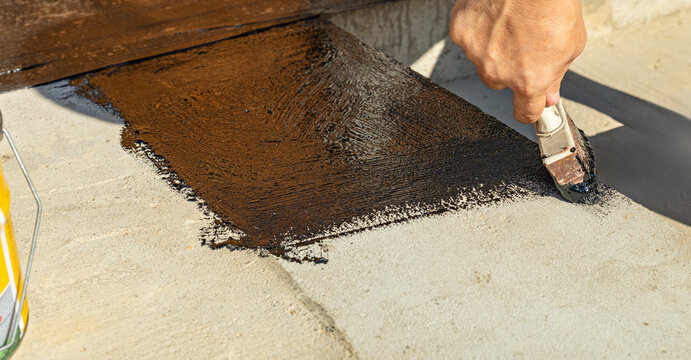 Construction techniques for waterproofing basement and foundations. Insulation material on the basement concrete wall. Waterproofing house foundation with spray on tar and roll waterproofing