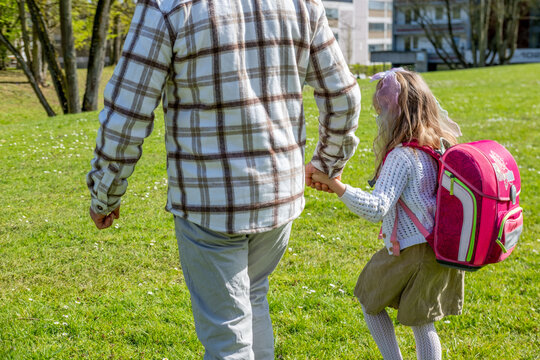 senior man leading young schoolgirl with backpack by hand, potential stranger danger scenario, child safety awareness, risk abduction, urban environment, protection concept, vigilance in public spaces