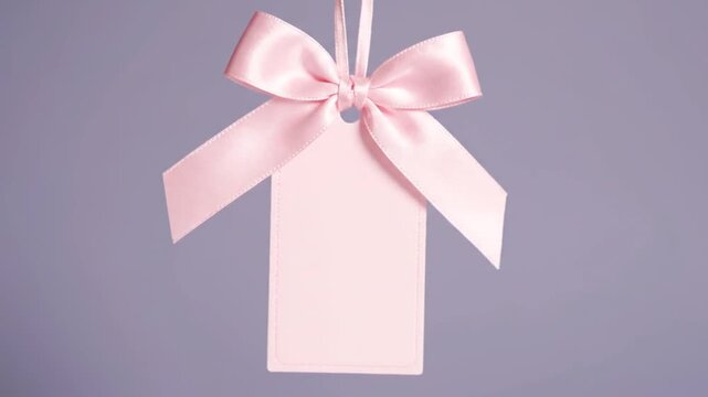 Pink gift tag with satin bow with purple background.