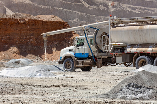 A specialized blasting truck discharges ammonium nitrate granules into a blast holes during explosives preparation at a copper mine.