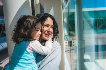 Obraz premium Mother and Cute toddler Daughter at the airport traveling together waiting for holidays flight, planes out of the window, family travelling