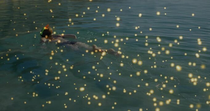 Woman kicking across water, mask and tube creating wake, gold overlay moving around her for travel