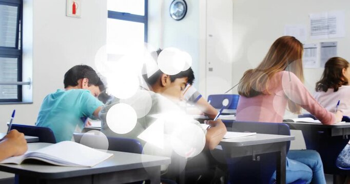 Students writing at desks while camera panning and bokeh overlays drifting, doing classwork