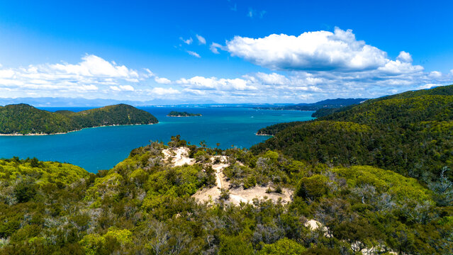 Aerial view of turquoise waters meeting verdant forests under a vast sky, a paradise of contrasts, Abel Tasman National Park, Tasman Region, New Zealand.