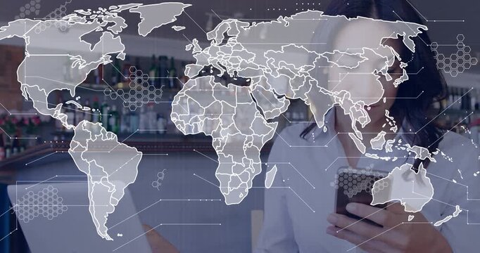 Woman tapping phone at counter and building map overlay while checking marketing data on laptop