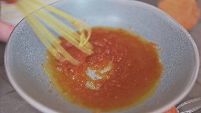 Yellow Whisk Stirring Amber Sauce Gently Closeup Of Home Cooks Hand Whisking Citrus Caramel Glaze In Ceramic