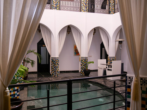 Traditional Moroccan riad interior with white arches and colorful zellige tilework pool Marrakesh