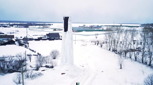 A frozen water tower. The water has turned to ice. It's abnormally cold. An ice-covered iron structure that holds water. An ice-covered iron water tower.
