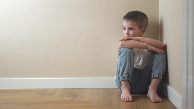 Young girl sitting on the floor. Sad lifestyle child sits on a corner and is punished. A teenage girl is traumatized by a violent incident. A little girl sitting on the ground.
