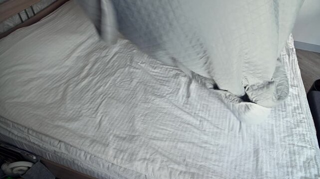 Bedding arrangement process showing quilted blanket on a bed in a bedroom