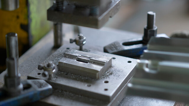 Close-up view of metal stamping die during precision machining in industrial workshop
