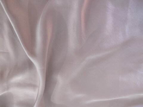 Texture de tissu satin rose poudr&eacute; avec reflets doux et plis soyeux