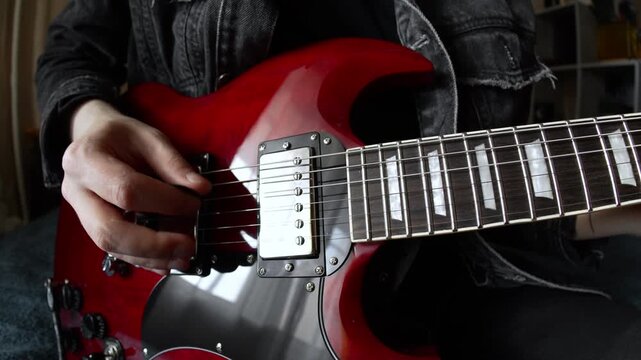 man in black denim playing electric red sg guitar in the day at home. Fisheye lens effect