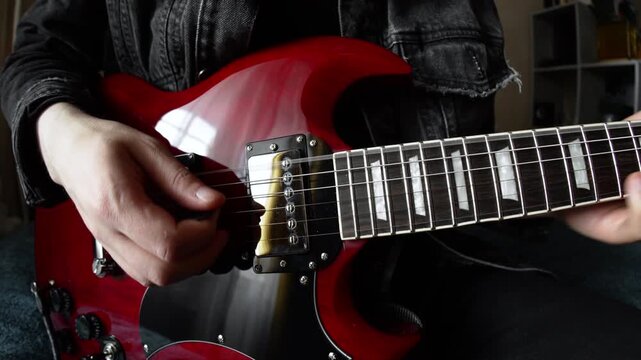 man in black denim playing electric red sg guitar in the day at home. Fisheye lens effect