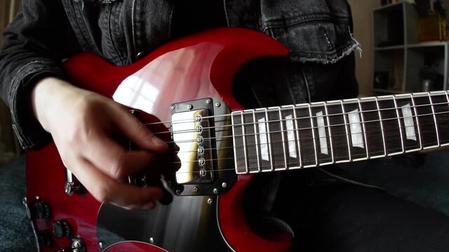man in black denim playing electric red sg guitar in the day at home. Fisheye lens effect