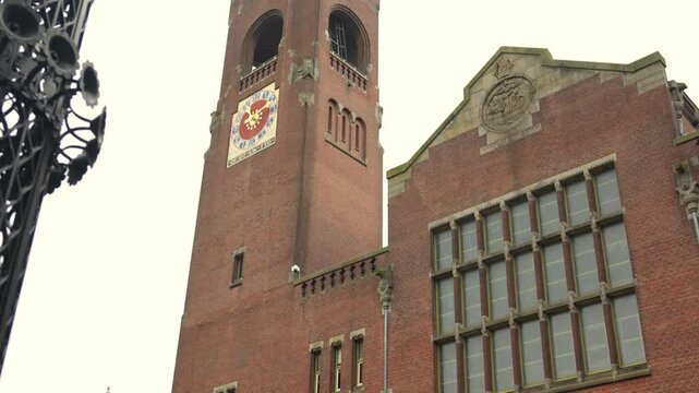 Historic Amsterdam clock tower and facade under overcast sky low angle view