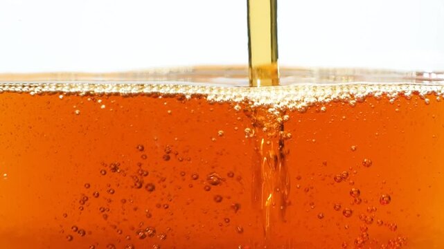 Thick stream of golden maple syrup pouring down macro slow motion.