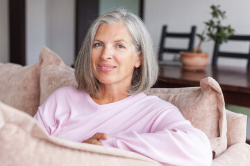 Portrait happy healthy middle aged woman sitting on comfortable couch at home © Tatyana Gladskih