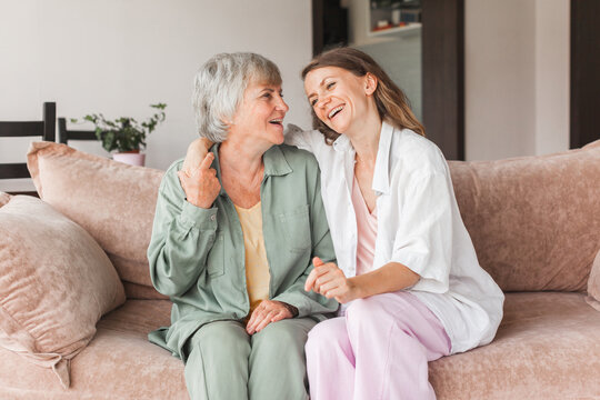 Older mature mother and grown millennial daughter laughing embracing, caring smiling young woman embracing happy senior middle aged mom