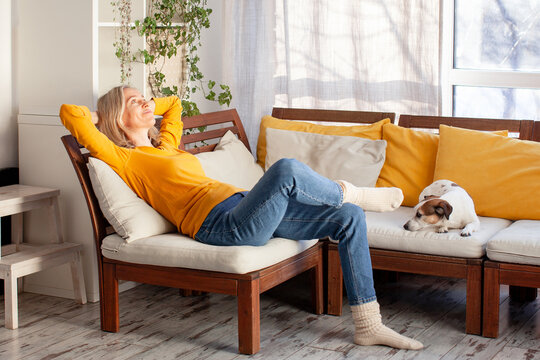 Happy beautiful relaxed mature woman relaxing on sofa at home. Smiling stylish middle aged 45s lady enjoying resting sitting on couch in living room, looking up.