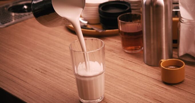 Pouring hot milk into glass for Latte Macchiato in slow motion