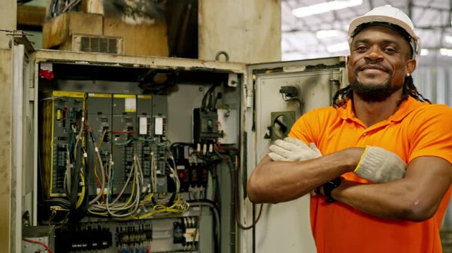 Electrician technician worker in hard hat safety gear at industrial factory, performing control panel wiring and maintenance, focused service on open electrical cabinet with circuit breaker repair