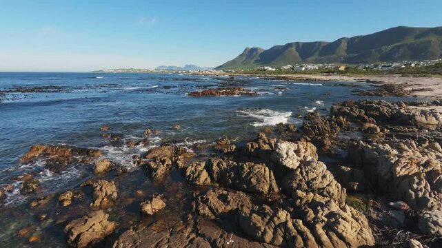 4k 30fps footage of the rugged, rocky Sandbaai coastline near Hermanus, Overberg, Western Cape, South Africa. Lovely view, breaking waves and pristine shoreline for travel and nature storytelling.
