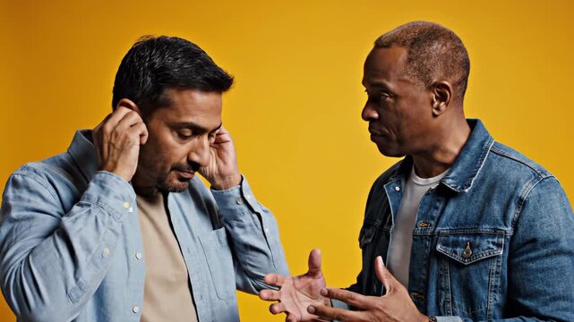 Man covering ears to avoid listening to another man arguing, symbolizing conflict, disagreement, and communication breakdown.