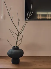 Fototapete Japandi Minimalist interior with dried branches in a dark textured vase on a wooden shelf. Beige ribbed wall background. Japandi style home decor.  © Евгений Бордовский