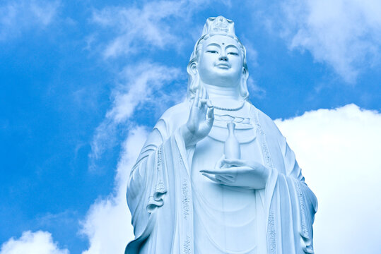 Low angle view of the giant white Lady Buddha statue (Guanyin) at Linh Ung Pagoda against a bright blue sky.