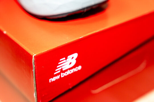 Warsaw, Poland - April 10, 2026: Close-up of a New Balance shoe box showcasing the brand logo prominently displayed against a bright red background, ideal for sports and fashion marketing.