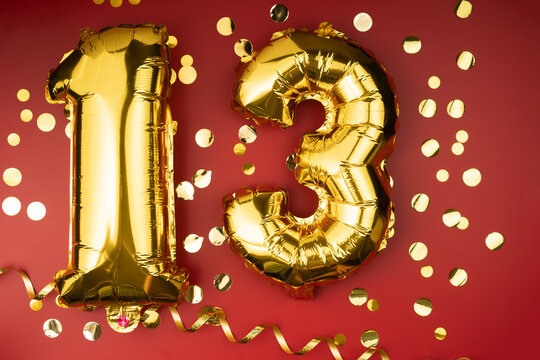 13th birthday celebration. Gold festive balloons number 13 year anniversary on red background with confetti. Birthday or wedding event.
