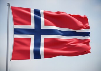 Fototapeta premium The vibrant red Norwegian flag with a blue cross bordered by white waving majestically on a flagpole under a clear sky